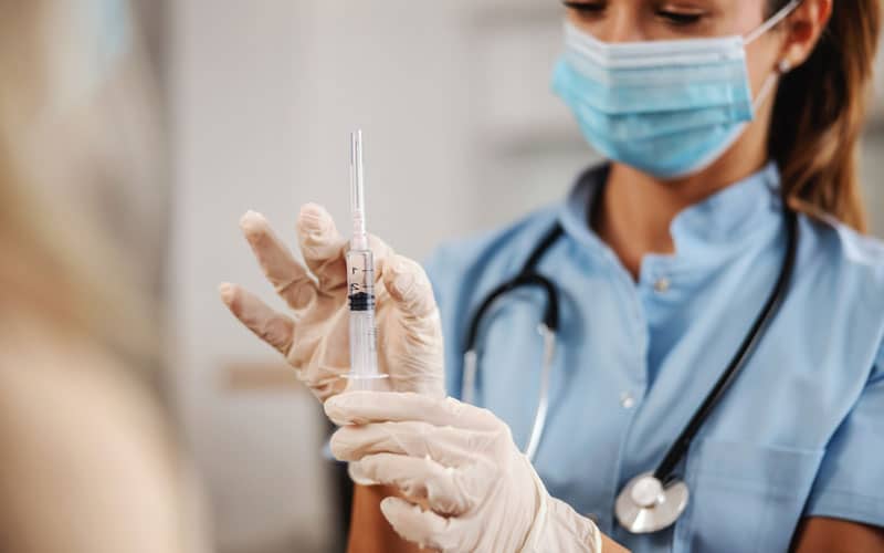 Infirmière préparant une seringue pour faire une injection à domicile chez un patient